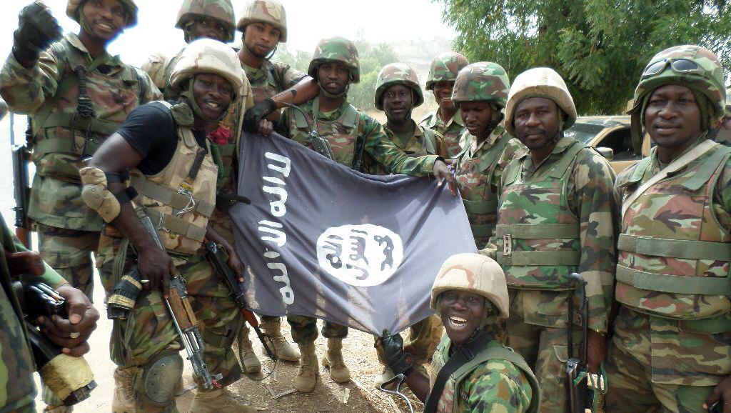 جنود نيجيريون مع علم جماعة "بوكوحرام" بعد تفكيكهم معسكرا للمجموعة خلال فبراير 2017.