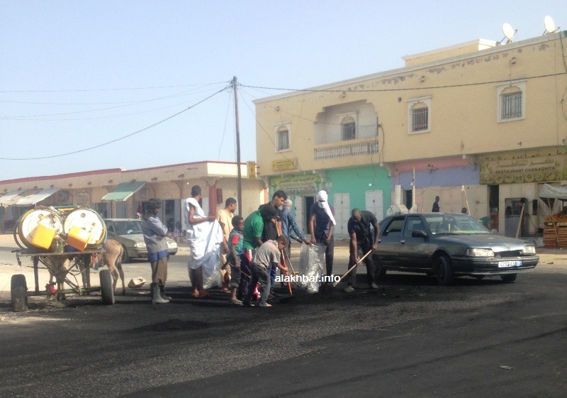 مواطنون يزيلون مخلفات احتجاجات أمس من منطقة المنعطف الثاني في حي السعادة "ملح" بمقاطعة توجنين (الأخبار)